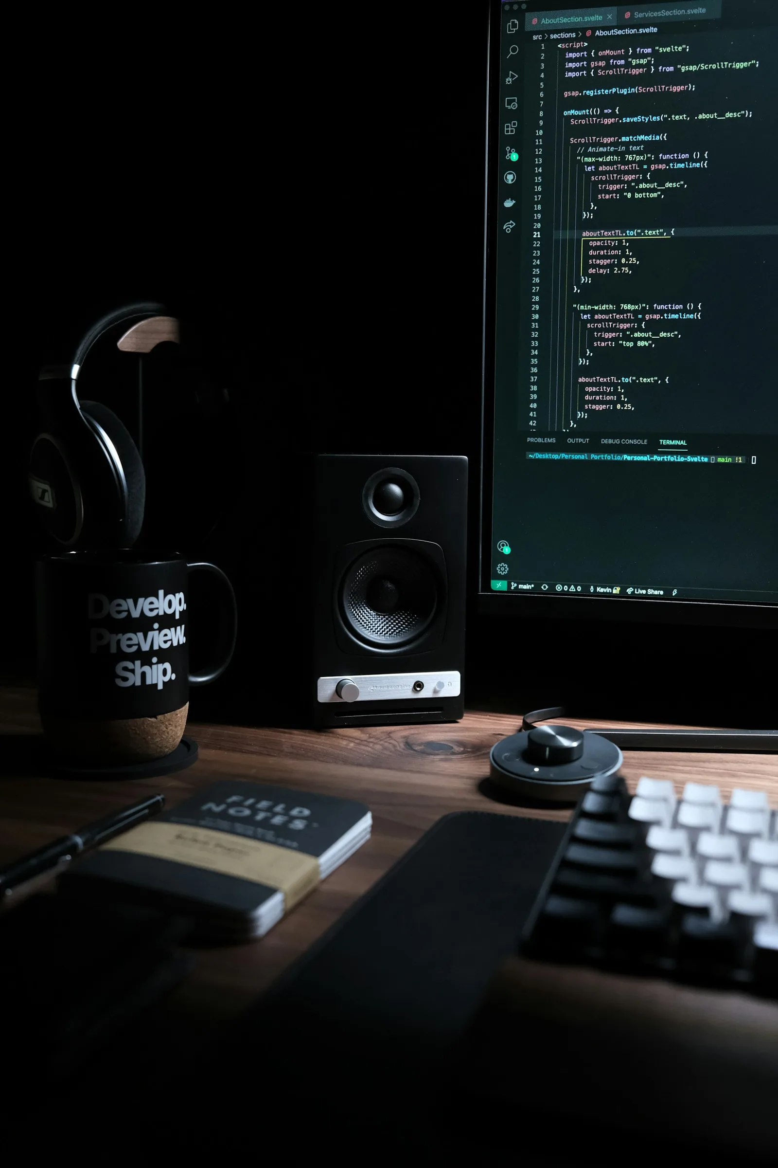 Computer monitor, speaker and headphones on a dark desk