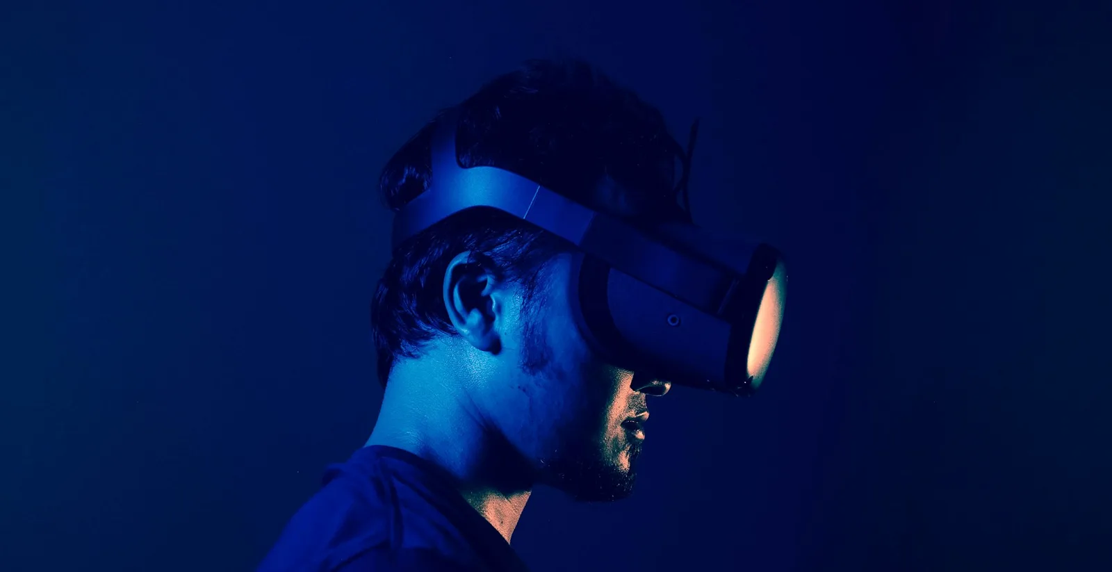 Side profile of a person wearing a VR headset under blue lighting